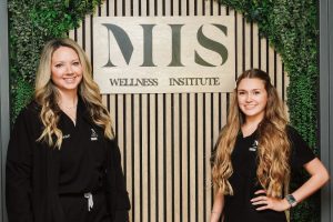 Nurses Kelly and Jordan in front of MIIS Wellness Institute sign